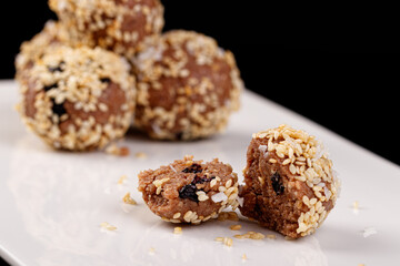 Beautiful candies with sesame seeds on a white plate on a black background