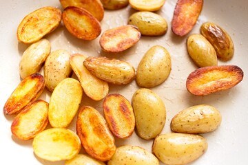 cooking fried potatoes in white pan