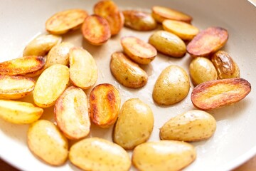 cooking fried potatoes in white pan