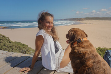 photo of a beautiful young woman smiling on the beach with her dog