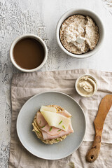 Modern  healthy breakfast. Buckwheat and rice cake with hummus, ham and cheese and hot drink on light background with napkin