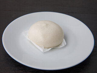 Salapao dim Sum China and thailand traditional street food, stuffed steamed bun on white plate on black wooden table
