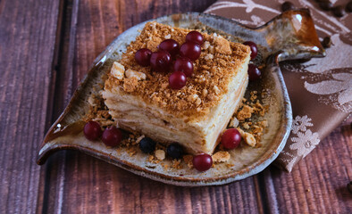 Homemade baked cake Napoleon, Millefeuille. Delicate custard cake garnished with berries. Against the background of a wooden table with a beautiful napkin and whole coffee beans