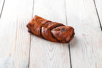 Freshly baked tasty bun on a white wooden table. Tasty baked goods straight from the bakery. White background.