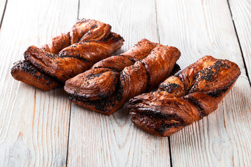 Freshly baked tasty bun on a white wooden table. Tasty baked goods straight from the bakery. White background.
