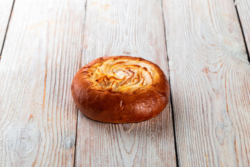 Freshly baked tasty bun on a white wooden table. Tasty baked goods straight from the bakery. White...