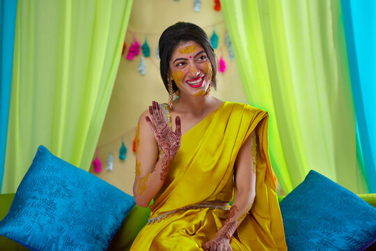 Indian bride looking away and gesturing on haldi ceremony