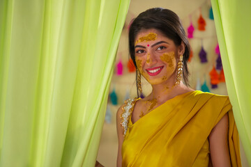 Portrait of a happy Indian bride with turmeric paste on face