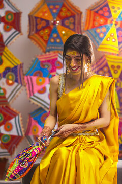 Indian bride sitting on stage with holding a umbrella on Haldi Ceremony