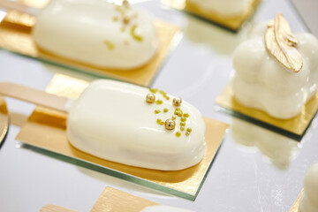White decorated cakes - popsicle in white chocolate glaze and golden sprinkles on a white background.
