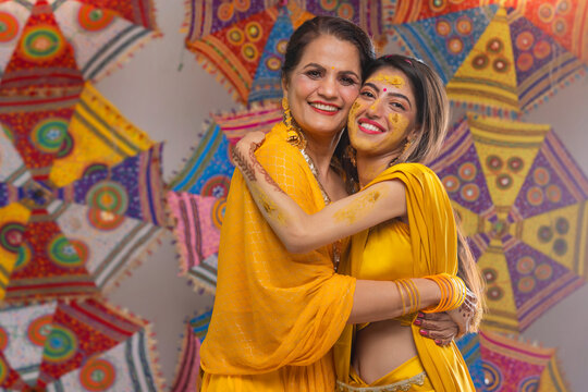 Portrait of Mother and daughter hugging and looking at camera during haldi ceremony