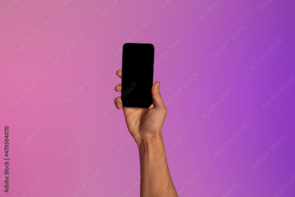 Poster unrecognizable young guy holding modern smartphone with empty screen, showing space for new mobile a