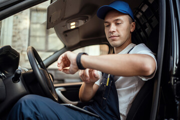 The driver of the courier service delivers food and goods to the house. A uniformed employee. Uses the phone.