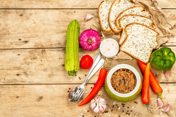 Vegan stew with a set of fresh vegetables. Chopped cooked ingredients, bread, cutlery, and spices