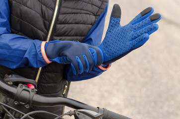 Fototapeta premium Close-up of a cyclist putting on sports gloves. Warm sports gloves on a woman's hand