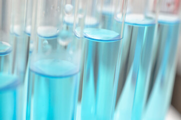 Medical laboratory test tubes with blue liquid close up, selective focus. Scientific laboratory research. Antiviral vaccine development