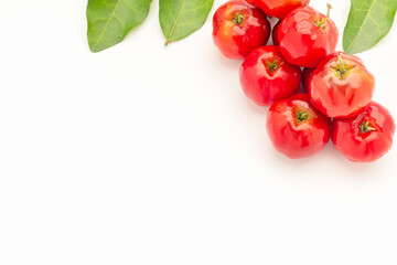 Pile of ripe red acerola cherries and green leaves isolated on a white background