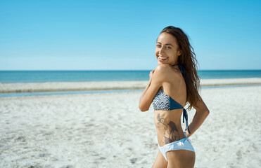 Cheerful bikini woman running on tropical paradise beach. Portrait of happy playful girl having fun during vacation