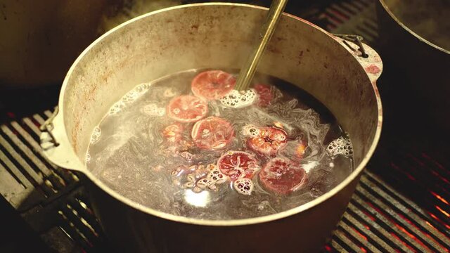 Cooking hot tasty mulled wine in big pot outdoors on winter local holiday market fair