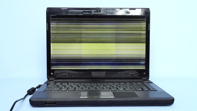 An old laptop with faulty display. Problems working on an outdated laptop. Threat of sudden breakdown and loss of unsaved information. Horizontal colored lines on faulty monitor display. 4K video
