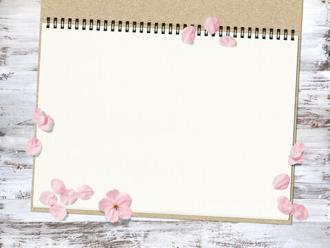 白塗りウッドデッキとスケッチブックに、桜の花が散る背景