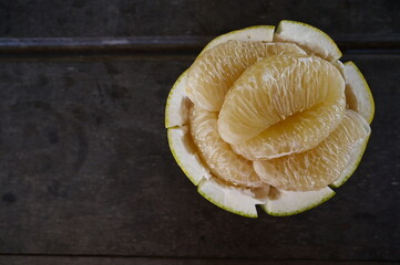 Pomelo rinds are made into a dish for placing the pulp of the fresh peeled pomelo for sale on table wood. in a fruit shop. Is fruit in the citrus family from Thailand that is sweet and sour delicious.