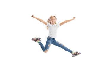 Fototapeta na wymiar Dynamic portrait of little girl, kid in casual clothes jumping, having fun isolated on white studio background.