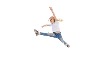 Fototapeta na wymiar Dynamic portrait of little girl, kid in casual clothes jumping, having fun isolated on white studio background.
