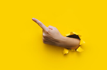 The forefinger points to the left up side. Yellow background. Place for advertising. Copy space....