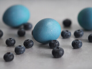 Easter eggs in blue tones with blueberries with a natural pattern. Waiting for the holiday. Gray concrete background and table decoration