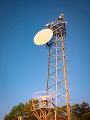 Antenna tower on the blue sky background over the forest