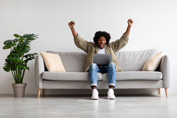 Online Win. Excited Black Male Celebrating Success With Laptop At Home