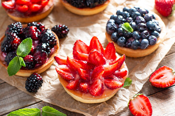 Tasty tartlets with berries on wooden table