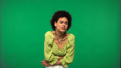 Obraz premium young african american woman in hoop earrings having stomach ache isolated on green