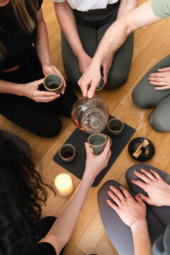 Woman pouring tea to her friends during tea ceremony.