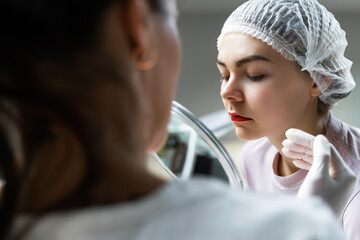 Permanent makeup artist and her client during lip blushing procedure