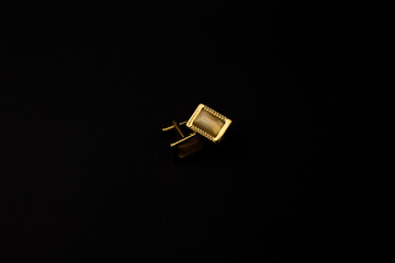 Gold men's cufflinks with stones lie on a black background