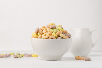 Colored flavored rings of cereals with milk on a white table, fruit loops or fruit hoops in a white...