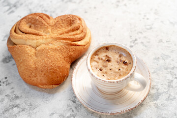 cappuccino and heart shaped bun on stone background for valentine's day