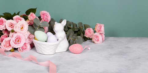 Easter bunny, colored eggs and pink flowers. Festive easter web banner with free text space