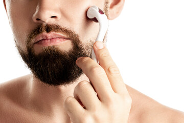 Handsome man using meso roller for better beard growth