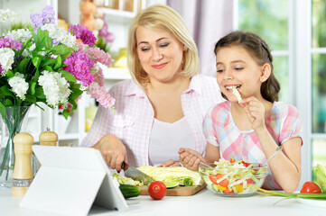 Cute little girl with her mother cooking together