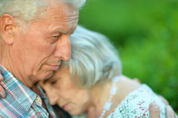 Unhappy senior couple posing in the summer park