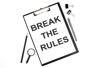 On a white background magnifier, a pen and a sheet of paper with the text BREAK THE RULES . Business concept
