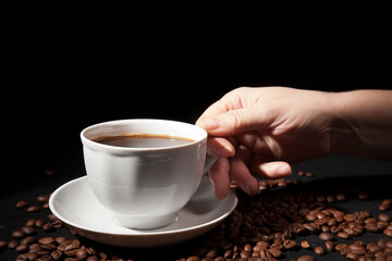 Cup of aromatic coffee with coffee beans on a dark background
