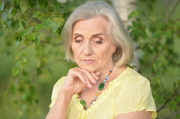 Portrait of sad senior beautiful woman in spring park