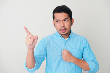 Adult Asian man showing resentment expression while pointing to someone