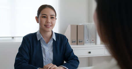 Asia woman real estate sale agent or trader advice sitting at lawyer office desk  smile trust talk in wealth service legal tax consult. HR people brief or coach for happy work plan in bank loan job. © ChayTee
