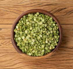 Raw dried green peas in a bowl over wooden table