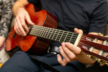 view of a person hand on a wooden handle near the strings of a guitar